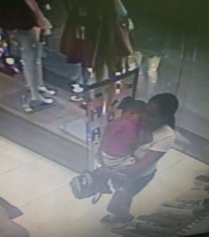 Mulher com criança no braço furta celular em loja do shopping