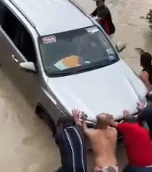 Cícero Cavalcante tenta passar por via inundada e carro precisa ser empurrado por Fernando Cavalcante e populares