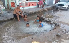 Crianças tomam banho em 'piscina' formada por vazamento da Casal em Maragogi