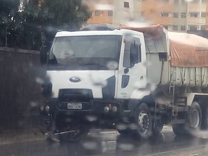 Motociclista vai parar embaixo de caminhão após desviar de buraco