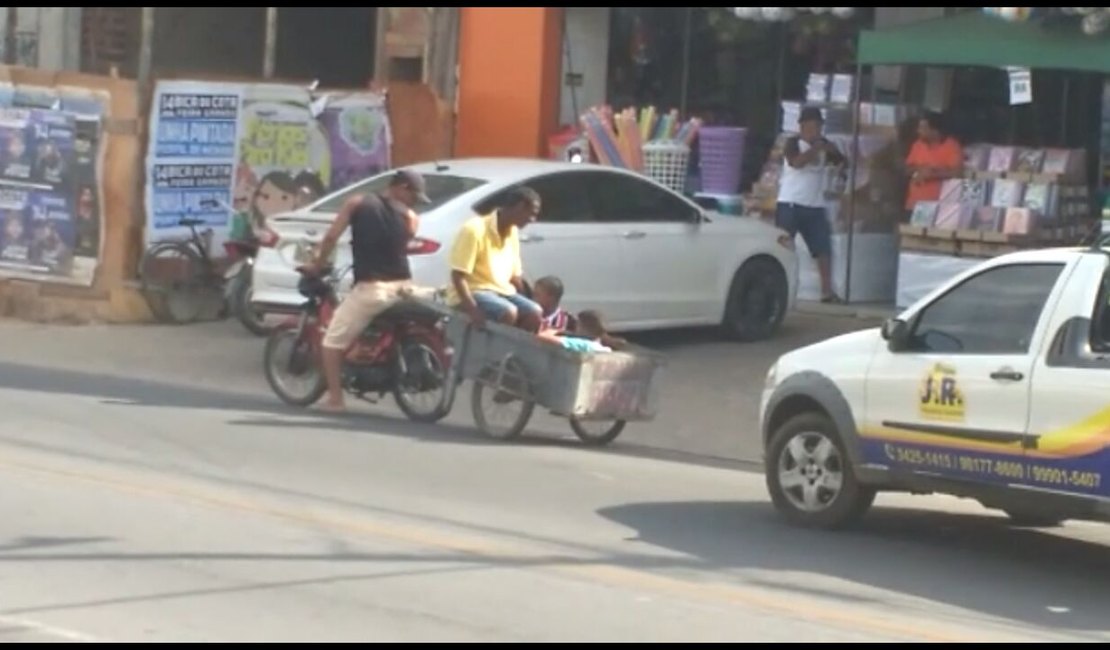 [Vídeo] Homem dirige moto puxando três pessoas num carrinho de mão