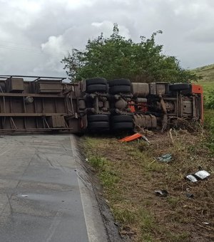 [Vídeo] Carreta tomba, fica atravessada na BR-104 e deixa motorista preso às ferragens