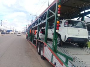 Carro é levado de caminhão-cegonha em frente a concessionária
