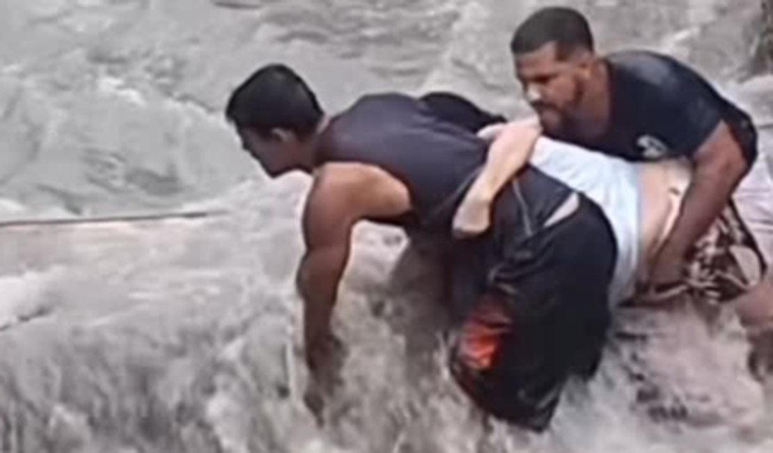 Homem usa corda para resgatar idosa durante enxurrada na periferia de Maceió