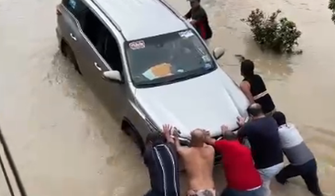 Cícero Cavalcante tenta passar por via inundada e carro precisa ser empurrado por Fernando Cavalcante e populares
