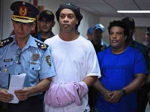 Após noite na prisão, Ronaldinho e Assis são algemados e levados para prestar depoimento