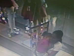Mulher com criança no braço furta celular em loja do shopping