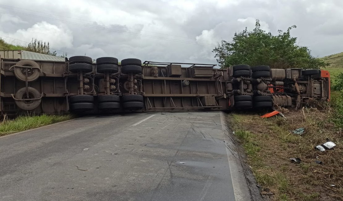 [Vídeo] Carreta tomba, fica atravessada na BR-104 e deixa motorista preso às ferragens