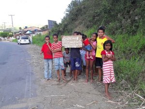 Crianças carentes erguem placa às margens de rodovia para pedir presentes