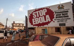 Pessoas passam por outdoor com alerta sobre o ebola na cidade de Freetown, em Serra Leoa