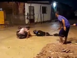 Motociclista tenta atravessar rua alagada e fica preso em buraco no Jacintinho