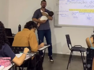 Professor segura bebê de aluna no colo durante a aula para ajudar aluna