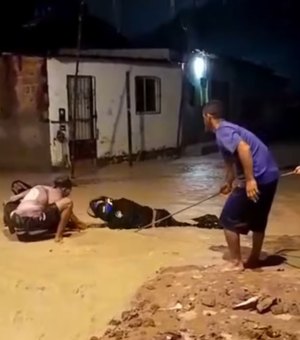 Motociclista tenta atravessar rua alagada e fica preso em buraco no Jacintinho