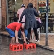 Homem improvisa ponte e ajuda pessoas a atravessar rua alagada